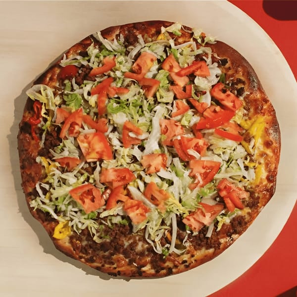 A Joey's Pizza taco pizza, topped with ground beef, shredded lettuce, and diced tomatoes.